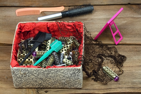 Ancient hairdresser set with hair curlers, razor blades, mirror, comb and hair net. Barber set in a luxury box on wooden table. Hairdo kit from last century.の写真素材