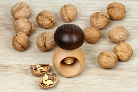 Wooden nutcracker in a shape of mushroom and walnuts. Screw type nut cracker with walnuts on wooden...