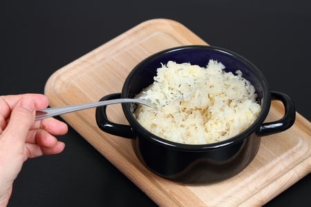 Sauerkraut on a fork and in a pot.  Sauerkraut (fermented or pickled cabbage) on a chopping board, black backgroundの写真素材
