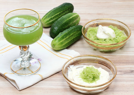 Several ways to prepare a facial mask and a delicious juice from cucumbers at home. Cucumbers and yogurt for smoothing, softening and hydrating skin and cucumber  drink in glass decorated with gold.の写真素材