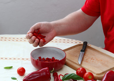 Man's hands holding cut red pepper. Young cook making vegetarian meal from tomatoes  and red peppers.の写真素材