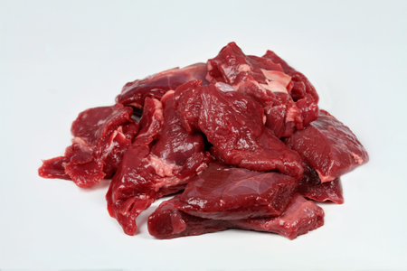 Raw deer meat ready for cooking venison ragout or goulash.  Pieces of game meat on the white...