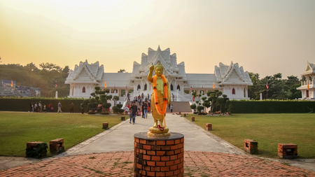 Lumbini, Nepal - November 10 2018: People and tourists admiring Rotal Thai Monastery of Lumbini. Gautam Buddha Statue in the foreground.のeditorial素材