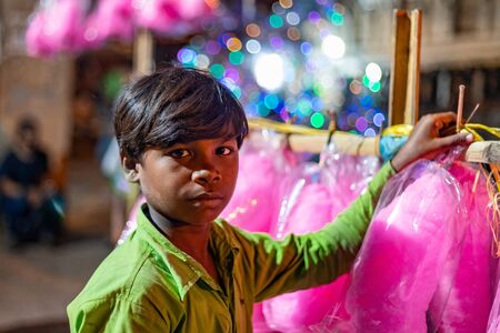 Kathmandu, Nepal - September 12 2019: Poor asian kid selling cotton candies at Indra Jatra Festival  in Kathmandu, Nepalのeditorial素材
