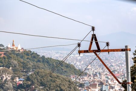 Electric pylon and wires transmitting electricity to the city. Blurred houses in the backgroundの写真素材