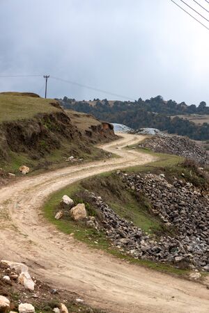 Curvy narrow dirt road in remote hilly regionの写真素材