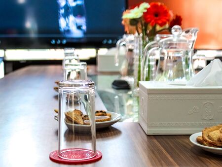 Business people sitting on a table for conference with cookies glass and jar of water placed on...