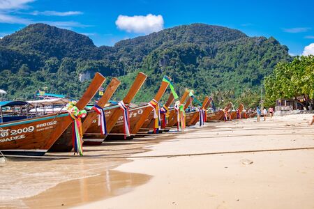 Phi Phi Island,  Thailand - November 26 2019: traditional wooden longtail boats parked at a beach in Phi Phi Island. Clear water and clean beach.のeditorial素材