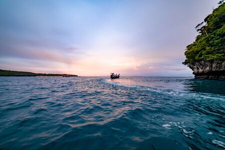 A boat sailing off during golden hour off the coast of Thailand.