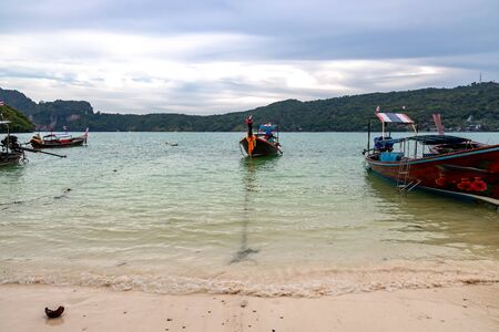 traditional wooden longtail boats parked at a beach in Phi Phi Island. Clear water and clean beach.の写真素材