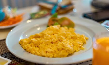 Scrambled egg presented on a white plate at breakfast table. Healthy Breakfast Concept.の写真素材