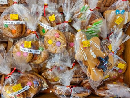 Handmade Christmas cookies are packed in a plastic bag lying on a rustic wooden tableの写真素材