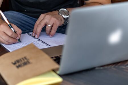 Hand of a young businessman taking notes with a fountain pen on a notecopy.  Student learning online. Blogger. selective focusの写真素材