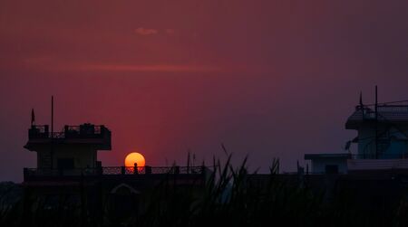 Silhouetted little girl playing on the terrace against the setting sun. People are not allowed to go out due to recent lockdown imposed amid concerns over coronavirus outbreak. selective focusの写真素材