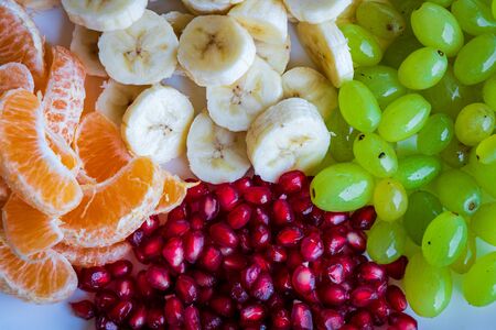 Healthy Breakfast Concept. Fresh fruits on the breakfast table. Close up of Grapes, banana, oranges, pomegranate. selective focusの写真素材