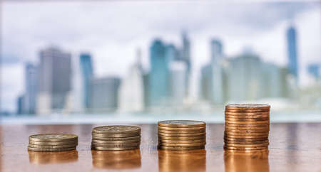 Savings Concept. Golden coins arranged in increasing order against the real-estate background.の写真素材