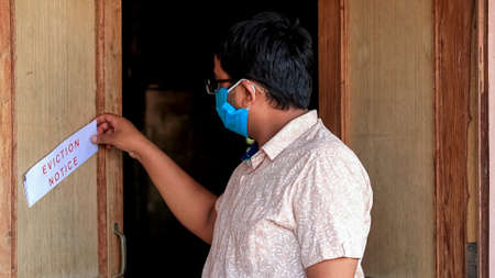 Asian man finds eviction notice on the door of the houseの写真素材