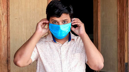 Protection from COVID-19 Concept. Man comes out of the house, wears mask before going out and...