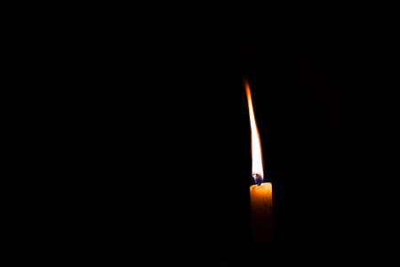 white wax candle burning in the dark isolated with copyspaceの写真素材