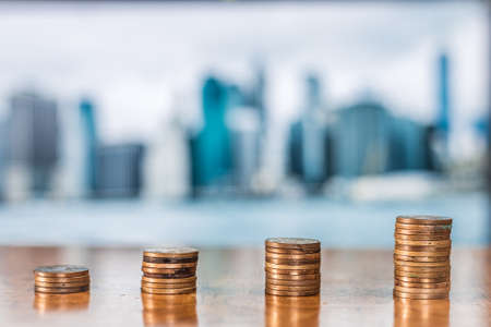 Savings Concept. Golden coins arranged in increasing order against the real-estate background.の写真素材