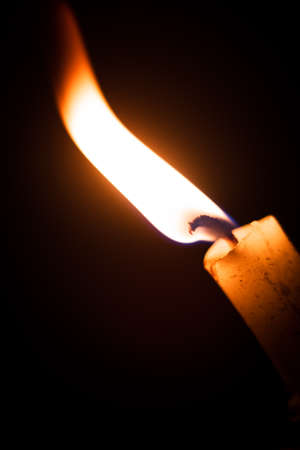 white wax candle burning in the dark isolated with copyspaceの写真素材