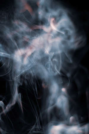 White smoke from incense stick isolated against dark backgroundの写真素材