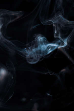 White smoke from incense stick isolated against dark backgroundの写真素材