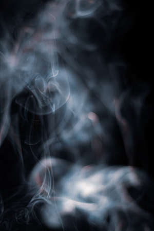 White smoke from incense stick isolated against dark backgroundの写真素材