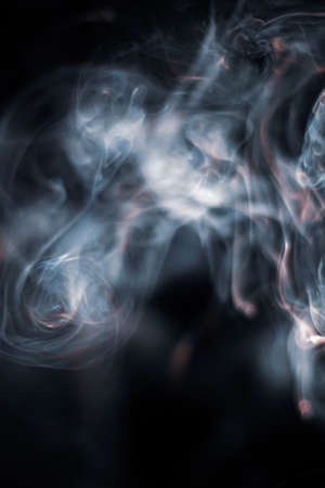 White smoke from incense stick isolated against dark backgroundの写真素材