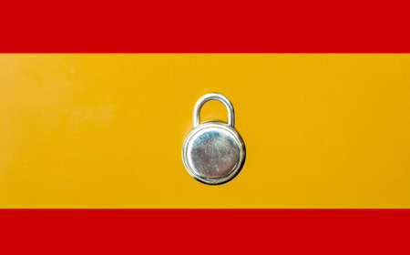 Concept Of Second Lockdown in Spain. Real padlock placed on top of flag of Spain to indicate second national lockdown in the country due to rise in COVID-19 cases.の写真素材