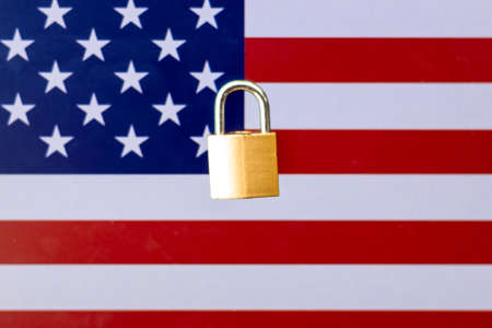Concept Of Second Lockdown in US. Real padlock placed on top of the American flag to indicate second national lockdown in US due to rise in COVID-19 cases.の写真素材
