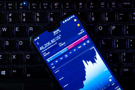Kathmandu, Nepal - February 8 2021: Stock value of Bitcoin on a smartphone against laptop keyboard. Bitcoin has spiked to the highest value yet after Tesla invested $1.5 Billion.のeditorial素材