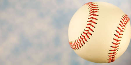 A close up of a baseball with a blue sky.の写真素材