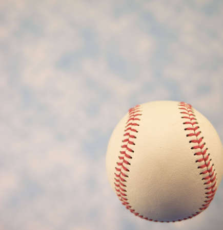 A close up of a baseball with a blue sky.の写真素材