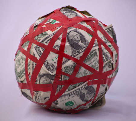 A shot of a ball of a bunch of dollar bills tied up in red tape.の写真素材
