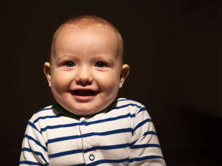 A close up of a happy baby in stripes.の写真素材