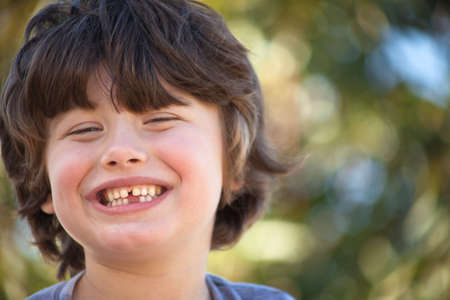 A close up of a young boy with a big smile and green background.