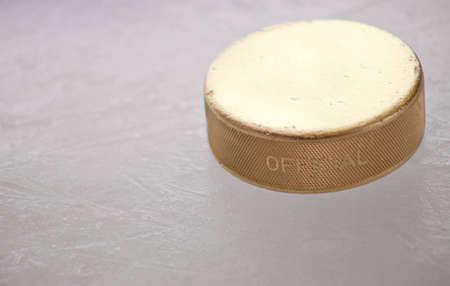 A close up of a gold ice hockey puck sitting on the ice.の写真素材