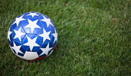 A close up of a stars and stripes soccer ball on grass.の写真素材