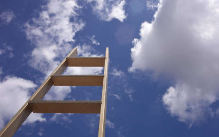 A close up of a gold ladder sticking up into a blue sky.の写真素材