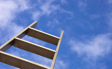 A close up of a gold ladder sticking up into a blue sky.の写真素材