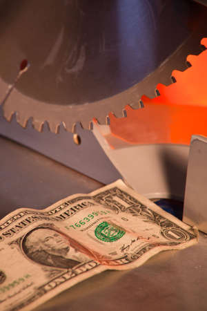 A close up of a dollar under a saw blade.の写真素材