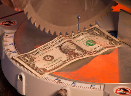 A close up of a dollar under a saw blade.の写真素材