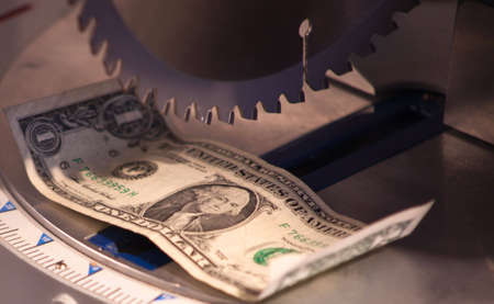 A close up of a dollar under a saw blade.の写真素材