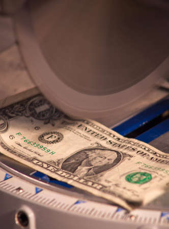A close up of a dollar under a saw blade.の写真素材