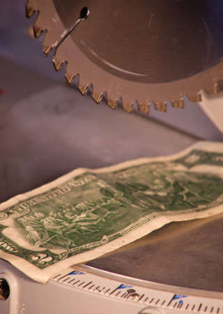 A close up of a Two dollar bill under a saw blade.の写真素材