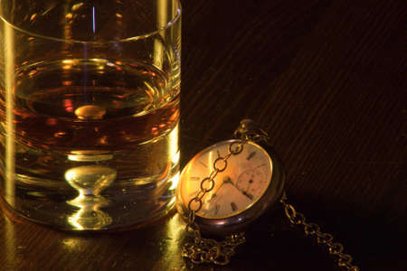 A close up of a pocket watch and low ball glass with whiskey.の写真素材