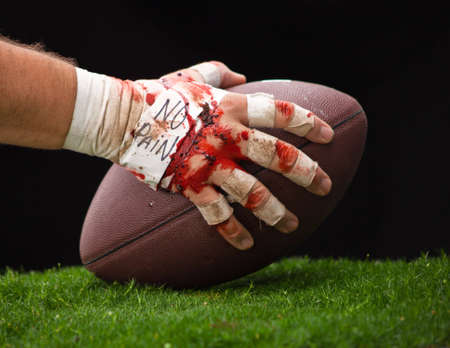 A close up of a beat up hand about to hike a football.の写真素材