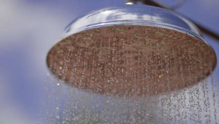 A close up of an outdoor shower with a blue sky background.の写真素材