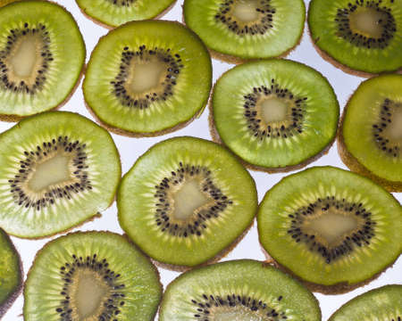 A close up of a bunch of kiwi fruit cut into cross section on a white background.の写真素材